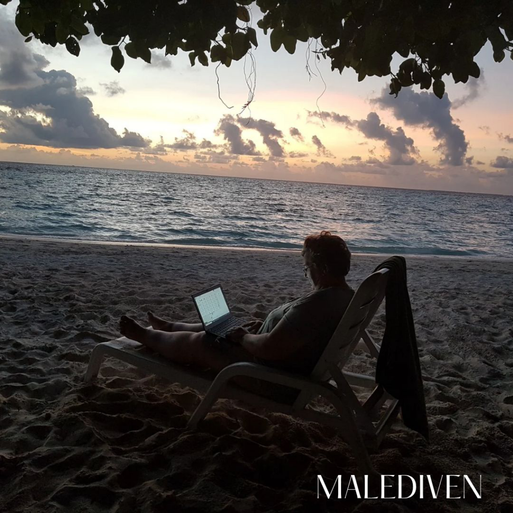 Anette mit Laptop am Strand Malediven